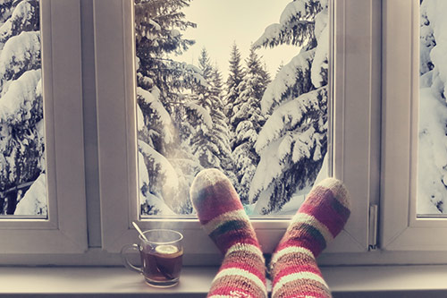 Tee und Socken vor einem verschneiten Fenster